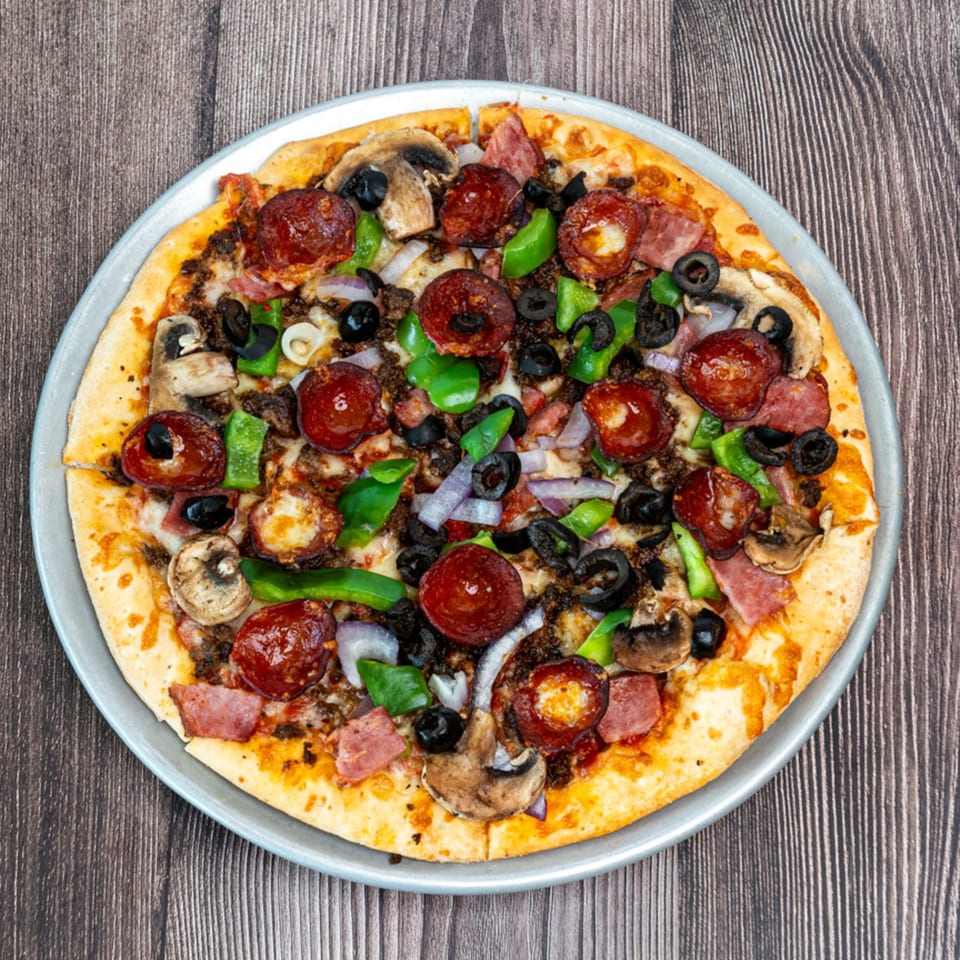 Ricco's Pizza with pepperoni, mushrooms, olives, green peppers, and onions on a metal tray.