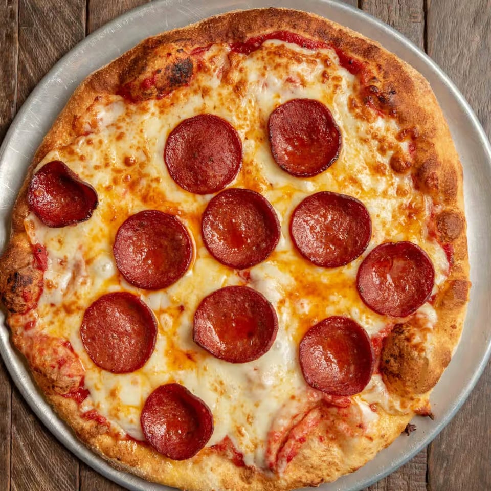 A freshly baked Ricco's pepperoni pizza with melted cheese on a metal pan.